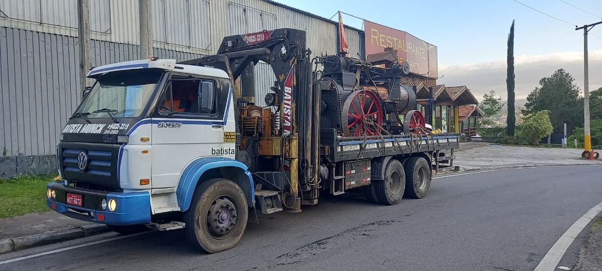 Caminhão munck Batista transportando máquina industrial de grande porte